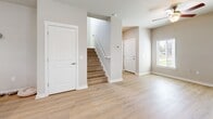 Located in Zephyrhills, FL, this two-story, 3-bedroom, 3-bathroom home offers a thoughtfully designed layout spread across two floors. The main level features an open-concept kitchen and living area with light wood-look flooring throughout. The kitchen is a standout, boasting white shaker cabinets, granite countertops, a subway tile backsplash, stainless steel appliances, and a central island with pendant lighting — ideal for both cooking and entertaining. The living area is bright and airy, enhanced by natural light from multiple windows and a ceiling fan for added comfort. A staircase with a handrail connects the two floors, with a convenient bathroom also located on the main level. Upstairs, three carpeted bedrooms each feature individual wall-mounted mini-split AC units and windows that invite natural light. The primary bedroom includes an en-suite bathroom with a granite-topped vanity, modern fixtures, and wood-look flooring. Additional bathrooms are clean and functional, with neutral tones and natural light. Closets provide practical storage throughout. The home's consistent warm neutral palette, modern finishes, and efficient layout create a comfortable and contemporary living environment.