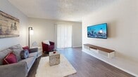 This single-story residence offers a thoughtfully designed layout with a clean, neutral palette and wood-style flooring running through the main living areas. The living room is a comfortable, open space featuring a textured ceiling, a sliding glass door with vertical blinds that invites natural light, and a wall-mounted media console ideal for entertaining. The space flows naturally into a secondary sitting area, maintaining a cohesive and welcoming atmosphere throughout.

The kitchen is outfitted with white cabinetry, marble-look countertops, a tile backsplash, and a built-in sink beneath under-cabinet lighting. A textured ceiling with flush-mount lighting and a dedicated dining counter add both functionality and charm to the space.

The bedrooms are carpeted for warmth and comfort, each equipped with ceiling fans and windows with blinds that allow for natural light. One bedroom features a spacious walk-in closet, providing ample storage. The bathrooms include white vanities with marble-style countertops, upper storage cabinets, and wood-look flooring. One bathroom is appointed with a vanity mirror and three-bulb light fixture, while the other includes a tub-shower combination.