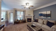 Located at 7010 W 124th St in Overland Park, Kansas, this single-floor residence offers a thoughtfully designed layout with a warm, refined aesthetic throughout. The living room serves as the focal point of the home, anchored by a tile-surround fireplace with a classic white mantle and complemented by a bold slate-blue accent wall, crown molding, plush carpeting, and a ceiling fan. Natural light filters in through large windows dressed with decorative curtains, creating an inviting atmosphere. An adjacent dining area features wainscoting, crown molding, hardwood-style flooring, and a wrought-iron chandelier, providing an elegant setting for formal meals. The kitchen is well-equipped with rich cherry cabinetry, granite countertops, a subway tile backsplash, stainless steel appliances, and durable wood-look flooring. The bedrooms are generously sized, each with ceiling fans, plush carpeting, and windows that bring in natural light. The primary bedroom connects to a spacious en-suite bathroom featuring a soaking tub, a dedicated vanity area with white cabinetry, wood-look flooring, and a walk-in closet. A second bedroom offers similar comfort and ample storage. Throughout the home, consistent design details including crown molding, neutral tones, and quality finishes create a cohesive and comfortable living environment.
