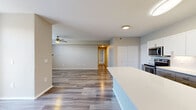 Located along Denver West-Marriott Blvd in Lakewood, Colorado, this well-appointed 2-bedroom, 2-bathroom residence offers a thoughtful layout across a single floor. The open-concept kitchen and living area serves as the heart of the home, featuring wood-look plank flooring, a ceiling fan, and a fireplace in the living room that adds warmth and character. The kitchen is a standout, showcasing a large white quartz island, crisp white cabinetry, a textured tile backsplash, stainless steel appliances including a range and built-in microwave, and a gold-accented faucet at the sink. A carpeted staircase with a wall sconce light leads to the entry, adding a welcoming touch. The spacious primary bedroom is finished with plush carpet, a ceiling fan, and direct access to a dedicated closet and private bathroom. The second bedroom also features carpet and a bright window with natural light. Both bathrooms are clean and functional — one includes a white vanity with modern fixtures and wood-look flooring, while the other features a soaking tub with a tiled surround. A dedicated closet provides additional storage. Neutral tones throughout create a calm, cohesive ambiance suited for comfortable everyday living.