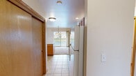 This single-floor, 2-bedroom, 2-bathroom home offers a thoughtfully designed layout with a comfortable mix of tile and carpet flooring throughout. The open living area is anchored by a tile-surround gas fireplace and vaulted ceiling with a ceiling fan, creating a warm and inviting atmosphere. Sliding glass doors lead to a private balcony, filling the space with natural light and offering pleasant outdoor views.

The kitchen is well-equipped with warm oak cabinetry, white appliances including a refrigerator, electric range, and built-in microwave, as well as a peninsula with pendant lighting overhead that connects seamlessly to the dining area. A stacked washer and dryer unit is conveniently tucked into a dedicated hallway space.

The generously sized primary bedroom features plush carpeting, direct access to a private bathroom, and a walk-in closet outfitted with built-in shelving and dual hanging rods. The en-suite bathroom includes tile flooring, a wood-toned vanity with ample counter space, and a walk-in shower with sliding glass doors. A second bedroom and additional full bathroom provide comfortable accommodations for guests or additional occupants. Two closets offer practical storage solutions throughout the home.