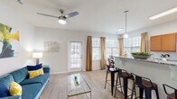 Located at 1100 Deer Harbor Dr in Garner, North Carolina, this single-floor residence offers a thoughtfully designed open-concept layout that seamlessly connects the main living areas. The living room is bright and welcoming, featuring plush carpeting, a ceiling fan, and direct access to the outdoors through a glass-paned door framed by large windows that flood the space with natural light.

The kitchen is a functional centerpiece, equipped with warm-toned wood cabinetry, granite countertops, stainless steel appliances including a refrigerator, microwave, and range, and hardwood flooring. A spacious peninsula with seating for multiple bar stools serves as both a prep area and a casual dining spot, illuminated by pendant lighting overhead.

Adjacent to the kitchen, a sun-drenched dining nook is surrounded by oversized windows with blinds and draped curtains, creating an ideal setting for meals in natural light.

The bedrooms are comfortably sized with soft carpeting and ample natural light. The bathroom features hardwood flooring, a wide vanity with wood cabinetry, and a shower-tub combination. A dedicated laundry room with side-by-side washer and dryer units and overhead shelving adds everyday convenience. Throughout, the neutral color palette and clean lines create a cohesive, modern ambiance.