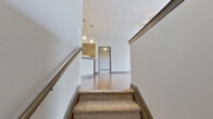 This single-floor residence offers a thoughtfully designed layout across a comfortable footprint, accommodating two bedrooms, two bathrooms, a combined kitchen and living area, a dedicated closet, and an in-unit laundry room. Rich hardwood flooring flows throughout the main living areas, complemented by neutral-toned walls and dark baseboards that provide a polished contrast throughout the space.

The kitchen serves as a central feature, showcasing warm wood cabinetry, granite countertops, a peninsula island with pendant lighting overhead, and a full suite of stainless steel appliances including a refrigerator, dishwasher, and range. A pass-through window connects the kitchen to the living area, which benefits from natural light provided by multiple windows fitted with blinds and offers access to an exterior door.

Both bedrooms are carpeted and generously proportioned, with the primary bedroom featuring a ceiling fan and ample room. The bathrooms mirror the kitchen's finishes, with granite-topped vanities and rich wood cabinetry. A dedicated laundry room houses a full-size washer and dryer with overhead shelving, adding everyday practicality to this well-finished residence.