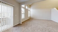This three-floor home in Reynoldsburg, Ohio offers a well-organized layout across its levels, providing ample living space for comfortable everyday life. The main level features an open-concept kitchen with warm wood cabinetry, granite-style countertops, a breakfast bar peninsula, and black appliances — all flowing seamlessly into the dining and carpeted living areas. A pantry adds convenient storage, and the living room benefits from a sliding glass door that invites natural light and outdoor views. The upper floor is home to two bedrooms, including a generously sized primary bedroom with vaulted ceilings, tall windows that bathe the room in natural light, and a large walk-in closet outfitted with wire shelving. Three full bathrooms are distributed throughout the home, each finished with tile flooring, warm wood vanities, and tub-shower combinations. A dedicated laundry area and multiple closets throughout add to the home's practicality. The lower level includes a basement with painted brick walls and concrete flooring, offering additional storage or utility potential. Completing the home is an attached two-car garage with an automatic opener. Neutral tones, carpet flooring in living spaces, and arched architectural details throughout lend a cohesive and welcoming ambiance.