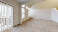 This three-floor home in Reynoldsburg, Ohio offers a well-organized layout across its levels, providing ample living space for comfortable everyday life. The main level features an open-concept kitchen with warm wood cabinetry, granite-style countertops, a breakfast bar peninsula, and black appliances — all flowing seamlessly into the dining and carpeted living areas. A pantry adds convenient storage, and the living room benefits from a sliding glass door that invites natural light and outdoor views. The upper floor is home to two bedrooms, including a generously sized primary bedroom with vaulted ceilings, tall windows that bathe the room in natural light, and a large walk-in closet outfitted with wire shelving. Three full bathrooms are distributed throughout the home, each finished with tile flooring, warm wood vanities, and tub-shower combinations. A dedicated laundry area and multiple closets throughout add to the home's practicality. The lower level includes a basement with painted brick walls and concrete flooring, offering additional storage or utility potential. Completing the home is an attached two-car garage with an automatic opener. Neutral tones, carpet flooring in living spaces, and arched architectural details throughout lend a cohesive and welcoming ambiance.