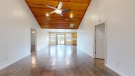 Located at 1775 Blessed Ln in Kerrville, TX, this single-story, 5-bedroom, 1-bathroom home offers a thoughtfully designed layout with standout architectural character throughout. The heart of the home is a generously sized open living area that immediately impresses with its soaring vaulted ceiling clad in warm knotty wood planks, complemented by a ceiling fan with integrated lighting and recessed fixtures. Polished concrete floors flow throughout the entire home, adding a modern, low-maintenance aesthetic that reflects natural light beautifully.

The combined kitchen and living area provides a seamless space for everyday living and entertaining, with natural wood cabinetry and multiple windows that draw in abundant natural light. A separate dining room and dedicated laundry room with upper storage cabinets add functional convenience. The five bedrooms are well-proportioned, each featuring ceiling fans and windows with blinds for comfort and privacy. The bathroom is finished with tile-surround tub and shower, wood cabinetry, and polished concrete floors.

A hallway connects the main living spaces to the bedroom wing, while two closets provide ample storage. Outside, a wood-decked patio overlooks a fenced backyard shaded by mature oak trees, offering a peaceful outdoor retreat. A storage shed completes the exterior.