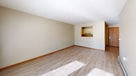 Located at 3175 Pennsylvania Ave in Dubuque, Iowa, this single-floor, two-bedroom, one-bathroom residence offers a well-organized and functional layout. Light-toned luxury vinyl plank flooring runs throughout the main living areas, creating a clean, cohesive aesthetic. The combined living and dining area is bright and open, highlighted by a set of French doors that invite natural light and provide outdoor access. A pass-through window connects the living space to the kitchen, enhancing the sense of openness. The galley-style kitchen is efficiently designed with ample white cabinetry, stone-patterned countertops, and black appliances including a refrigerator, range, and dishwasher. Both bedrooms feature plush carpeting, ceiling fans with light kits, and baseboard heating. The primary bedroom includes a built-in closet, while four total closets throughout the unit ensure generous storage. The full bathroom is well-appointed with a tub/shower combination fitted with grab bars, a single-sink vanity, and a large mirror. A dedicated laundry area with wire shelving and a utility hookup adds everyday convenience. Neutral wall tones and consistent finishes throughout give the space a tidy, move-in-ready appeal.