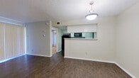 This single-floor residence offers a functional and well-organized layout designed for comfortable everyday living. The living room serves as the heart of the home, featuring rich dark hardwood-style flooring, a textured ceiling, and a classic white brick fireplace with a raised hearth — a standout architectural detail that adds warmth and character to the space. Vertical blinds across a large sliding door allow for natural light control and access to the outdoors.

The adjacent dining area flows seamlessly from the living room and is illuminated by a pendant light fixture. A pass-through window connects the dining space to the kitchen, enhancing the open feel between the two areas. The kitchen is well-appointed with crisp white cabinetry, light-toned countertops, and a full suite of black appliances, including a refrigerator, electric range, and over-the-range microwave.

The bedrooms are finished with plush carpeting and feature vertical blinds over windows, providing ample natural light. One bedroom includes a ceiling fan with light kit and a mirrored sliding closet, offering generous storage.

The bathroom presents a double-sink vanity with white cabinetry, light countertops, and a well-lit mirror, leading to a separate shower and tub area for added convenience.
