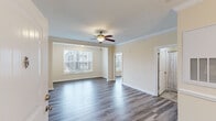 Located at 457 Stone Monument Dr. in Wake Forest, NC, this thoughtfully designed one-bedroom, one-bathroom residence offers a comfortable and functional living experience across a single floor. The open living room features smooth hardwood-style flooring, elegant crown molding, a ceiling fan with light fixture, and multiple windows that invite ample natural light. The neutral warm-beige palette throughout creates a cohesive and inviting ambiance. The kitchen is well-appointed with rich warm-toned cabinetry, granite countertops, a stainless steel sink, and a full suite of stainless steel appliances including a refrigerator, range, microwave, and dishwasher. Adjacent to the kitchen, the dedicated dining area showcases tile flooring, a stylish chandelier, and classic chair-rail molding. The spacious primary bedroom includes hardwood-style flooring, a large window for natural light, and access to a dedicated closet. The bathroom features tile flooring, a granite-topped vanity with warm wood cabinetry, and a tub-shower combination. Crown molding details in the main living areas add a refined finishing touch throughout this well-maintained residence.
