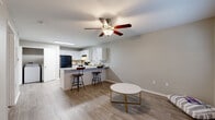 This single-story, one-bedroom, one-bathroom unit on Ford Avenue in Springdale, Arkansas offers a well-organized layout designed to maximize its compact footprint. The open-concept living and kitchen area forms the heart of the space, finished with light wood-look flooring and neutral gray walls that create a clean, cohesive aesthetic. A ceiling fan with a light fixture anchors the living area, while large windows fitted with white horizontal blinds allow natural light to fill the room.

The kitchen is efficiently designed with white shaker-style cabinetry, granite-look countertops, and black appliances including a refrigerator, electric range, and dishwasher. A peninsula with bar seating connects the kitchen to the living area, providing both additional prep space and casual dining. A dedicated closet and additional storage areas are accessible from the main corridor.

The bedroom features plush carpeting, a ceiling fan, and a window with blinds that introduces natural light. The bathroom is finished with wood-look flooring, a white vanity with granite-look countertops, a framed mirror, and overhead cabinetry. Overall, the space presents a tidy, move-in-ready environment with consistent finishes throughout.