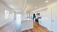 Located at 301 W Roosevelt St in the heart of Phoenix's vibrant Roosevelt Row arts district, this modern single-story home offers 2 bedrooms and 3 bathrooms within a well-appointed, open-concept layout. Warm wood-look flooring runs throughout, complementing the crisp white walls and clean-lined design that define the space.

The combined living, dining, and kitchen area forms the heart of the home. The kitchen features a large central island with a white quartz countertop and built-in sink, white shaker cabinetry, stainless steel appliances, and a striking cluster of cylindrical pendant lights overhead. Recessed lighting and large windows fill the space with natural light, while a sliding glass door opens to a private patio.

Both bedrooms are generously sized, with the spacious primary bedroom offering multiple windows framing views of the Phoenix skyline and palm trees. Each bedroom benefits from ample closet space, with five closets distributed throughout the home. The bathrooms are finished in a modern style, with white vanities, large mirrors, and marble-surround shower and tub combinations. Additional conveniences include a dedicated laundry room, pantry, and entrance foyer, making this a complete and functional urban residence.