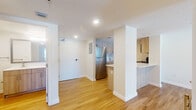Located on NE 126th St in North Miami, FL, this single-floor residence offers a clean, modern aesthetic defined by light wood flooring, crisp white walls, and recessed lighting throughout. The open-concept layout connects the living area seamlessly to the kitchen, which serves as a functional centerpiece of the home. The kitchen is outfitted with light wood cabinetry, white quartz countertops, a stainless steel refrigerator, stainless steel range and microwave, a subway tile backsplash, and a peninsula that provides additional counter space and defines the transition between the kitchen and living areas. The spacious living area is bathed in natural light and offers a generous, flexible floor plan. The bedrooms are well-proportioned, featuring the same warm wood flooring, wall sconce lighting, and windows with shuttered blinds that invite abundant natural light while maintaining privacy. The bathroom is thoughtfully finished with a wood-toned vanity, white quartz countertop, a framed mirror, and a full tub-shower combination with marble-style tile surround. Textured ceilings add a subtle architectural detail throughout the space, while the consistent flooring and neutral color palette create a cohesive, inviting atmosphere ideal for comfortable everyday living in the heart of North Miami.
