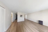 This efficiently designed 1-bedroom, 1-bathroom unit in New York Mills, NY offers a practical single-floor layout that maximizes every square foot. The open-concept living and kitchen area forms the heart of the space, featuring light wood-tone flooring that flows throughout. The living area is bathed in natural light from large windows with floor-to-ceiling curtains and a sliding glass door that opens to the outdoors, providing a bright and airy atmosphere. A baseboard heating unit and a wall-mounted air conditioner ensure year-round comfort.

The galley-style kitchen is well-appointed with white cabinetry, stainless steel appliances including a refrigerator, dishwasher, electric range, and microwave, complemented by a double basin sink and ample counter space. Neutral walls and clean lines give the kitchen a crisp, functional aesthetic.

The spacious bedroom offers a generous footprint with room for a large bed and additional furnishings. It includes a dedicated closet with bifold doors, providing organized storage. The bathroom features a shower-tub combination and continues the light wood flooring found throughout the unit. A separate closet adds additional storage to complete this well-organized home.
