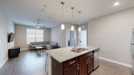 Located at 801 W 4th Ave in Stillwater, Oklahoma, this well-designed unit offers four bedrooms and four bathrooms across a thoughtfully laid-out single floor. The open-concept kitchen and living area serves as the heart of the home, where rich dark wood cabinetry pairs with a striking granite-topped island — complete with bar seating and pendant lighting — to create an inviting, functional space. Stainless steel appliances, a subway tile backsplash, and recessed lighting add a polished, contemporary feel. The living room features durable wood-style flooring, a wall-mounted TV setup, and a ceiling fan with light fixture, with natural light streaming in through large windows fitted with blinds. Each of the four bedrooms is carpeted for comfort, equipped with a ceiling fan, and includes a closet with double doors. Several bedrooms feature private or adjacent bathrooms, each outfitted with a full tub-shower combination, chrome fixtures, and wood-style flooring. The neutral color palette throughout lends a clean, modern aesthetic, while the consistent finishes across rooms create a cohesive living environment well-suited for shared occupancy.