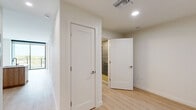 Located at 3411 N Federal Hwy in Fort Lauderdale, FL, this thoughtfully designed one-bedroom, two-bathroom residence offers a clean, modern aesthetic throughout. Light wood-plank flooring flows seamlessly across the entire space, complementing the bright white walls and creating a warm, airy ambiance.

The kitchen is a standout feature, showcasing a contemporary design with white upper cabinetry, warm wood-toned lower cabinets, a textured penny-tile backsplash, and a sleek peninsula with a white quartz countertop and integrated sink. Stainless steel appliances, including a refrigerator, range, and built-in microwave, complete the space. Track lighting overhead adds both function and style.

The bedroom is a quiet, light-filled retreat with a large window, clean lines, and ample room. A dedicated closet provides convenient storage. The hallway connects the living areas to two well-appointed bathrooms, each featuring light wood-tone vanities with white countertops, tiled shower enclosures, and modern fixtures. A stacked in-unit washer and dryer adds everyday convenience.

Recessed lighting, crisp white panel doors with brushed nickel hardware, and neutral tones throughout contribute to a polished, cohesive interior. A sliding glass door opens to an outdoor balcony, bringing in natural light and offering a connection to the surrounding Fort Lauderdale environment.