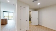 Located at 3411 N Federal Hwy in Fort Lauderdale, FL, this thoughtfully designed one-bedroom, two-bathroom residence offers a clean, modern aesthetic throughout. Light wood-plank flooring flows seamlessly across the entire space, complementing the bright white walls and creating a warm, airy ambiance.

The kitchen is a standout feature, showcasing a contemporary design with white upper cabinetry, warm wood-toned lower cabinets, a textured penny-tile backsplash, and a sleek peninsula with a white quartz countertop and integrated sink. Stainless steel appliances, including a refrigerator, range, and built-in microwave, complete the space. Track lighting overhead adds both function and style.

The bedroom is a quiet, light-filled retreat with a large window, clean lines, and ample room. A dedicated closet provides convenient storage. The hallway connects the living areas to two well-appointed bathrooms, each featuring light wood-tone vanities with white countertops, tiled shower enclosures, and modern fixtures. A stacked in-unit washer and dryer adds everyday convenience.

Recessed lighting, crisp white panel doors with brushed nickel hardware, and neutral tones throughout contribute to a polished, cohesive interior. A sliding glass door opens to an outdoor balcony, bringing in natural light and offering a connection to the surrounding Fort Lauderdale environment.