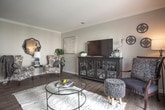 Located at 553 Settlers Landing Rd in Hampton, Virginia, this single-floor residence offers a well-designed layout that balances comfort and functionality. The open-concept living area is a standout feature, showcasing rich hardwood-style flooring, crown molding, and large sliding glass doors that flood the space with natural light and provide access to an outdoor balcony. The living room comfortably accommodates distinct seating and entertainment areas, flowing seamlessly toward the dining space and kitchen. The kitchen is outfitted with warm honey-toned cabinetry, dark granite-style countertops, stainless steel appliances, and durable wood-look flooring — a practical yet attractive space for cooking and entertaining. The primary bedroom features plush carpet, generous natural light through shuttered windows, and a connected en-suite bathroom with a vanity, tub-shower combo, and wood-look tile flooring. A second bedroom offers equal comfort with carpeted floors, bright windows, and versatile space. The second full bathroom mirrors the clean, neutral aesthetic of the primary bath. Throughout, the residence maintains a cohesive palette of soft grays and warm neutrals, creating a calm and inviting ambiance well-suited to everyday living.