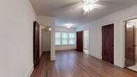 Located at 833–879 N Water St in Milwaukee's vibrant cityscape, this single-floor unit combines classic character with functional design. Rich, dark hardwood floors extend throughout the main living areas, complemented by crisp white walls and bold dark wood doors that add a timeless architectural contrast.

The main living area is generously proportioned, featuring a ceiling fan overhead and natural light streaming through multi-pane windows fitted with blinds. A spacious walk-in closet provides ample storage, while multiple doorways connect the rooms in a practical, well-organized layout.

The kitchen is a compact and efficient space, equipped with a gas range, refrigerator, white cabinetry, and a built-in countertop — offering all the essentials in a clean, light-toned setting with tile flooring.

The bathroom retains a charming vintage aesthetic, showcasing classic white hex-tile flooring, white subway wall tiles with black accent trim, a pedestal sink, a soaking bathtub with shower, and a cast iron radiator — all elements that speak to the building's historic character.

Baseboard heating is present throughout, and additional windows allow natural light into the secondary rooms. The overall ambiance is one of understated, classic charm, well-suited for those who appreciate traditional architectural details in a well-situated Milwaukee location.