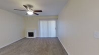This single-floor residence offers a thoughtfully laid-out 2-bedroom, 2-bathroom floor plan designed for comfortable everyday living. The living room serves as the heart of the home, featuring plush carpeting, a ceiling fan with light fixture, a charming white-mantled fireplace, and a sliding glass door with vertical blinds that allows natural light to fill the space. A dedicated entry area provides a clean transition into the home, complete with a classic six-panel front door and an electrical panel nearby.

The kitchen is outfitted with rich dark-wood cabinetry, a light granite-style countertop that extends as a breakfast bar, recessed lighting, a white appliance suite including a range and refrigerator, and a sink with ample cabinet storage — all arranged in an efficient galley-style layout.

The primary bedroom is a well-sized retreat with carpeted flooring, a ceiling fan, and natural light from a window with blinds. It connects to a private bathroom featuring a wood-toned vanity with a granite-style countertop, hardwood-style flooring, and access to a dedicated walk-in closet with built-in shelving and a full-length hanging rod. The second bedroom is cozy and carpeted with neutral walls. Both bathrooms are clean and functional, each equipped with a full soaking tub and shower combination.