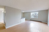 Located at 450 Victoria Ave in Windsor, Ontario, this 2-bedroom, 2-bathroom unit offers a well-designed, single-floor layout with a clean and modern aesthetic. Light hardwood flooring runs throughout the space, complementing the soft grey walls and white trim that create a bright, cohesive atmosphere.

The open-concept living, dining, and kitchen area forms the heart of the unit. A peninsula-style breakfast bar separates the kitchen from the living and dining zones, making it ideal for both casual meals and entertaining. The kitchen is appointed with white cabinetry, grey countertops, white subway tile backsplash, and a full suite of stainless steel appliances including a refrigerator, stove, and microwave. Natural light fills the living area through a large window offering treetop views.

The primary bedroom is generously sized, featuring a sliding glass door that opens to a balcony with city views. The second bedroom provides a comfortable, quiet retreat. Both rooms are finished with the same warm hardwood flooring and neutral tones.

The two bathrooms are clean and functional. One features a white tiled tub-shower surround, while the second offers a modern vanity with a wide mirror and tile flooring. A dedicated closet and baseboard heating throughout complete this well-appointed unit.