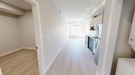 Located in the vibrant community of 17th Avenue SW in Calgary, this two-bedroom, one-bathroom unit offers a clean, contemporary design throughout. Light-toned vinyl plank flooring runs seamlessly across the entire space, complementing the crisp white walls and neutral palette that give the unit a bright, modern feel.

The kitchen is efficiently designed with a galley-style layout, featuring two-tone cabinetry — warm wood uppers paired with slate-blue lower cabinets — white tile backsplash, light countertops, and a full suite of stainless steel appliances including a refrigerator, stove, and dishwasher. Recessed lighting illuminates the kitchen area, and a stacked in-suite washer and dryer are conveniently tucked into an adjacent closet.

The primary bedroom is a comfortable size, offering a large window that fills the room with natural light and frames views of the surrounding neighbourhood and tree canopy. The second bedroom is a cozy, functional space with a built-in closet featuring classic panel doors. Both rooms benefit from baseboard heating.

The bathroom is finished in a clean, modern style with a full soaker tub and shower combo, white surrounds, and matte black fixtures that add a sharp contrast. A wide vanity with a light countertop completes the space. The overall ambiance is fresh, functional, and move-in ready.