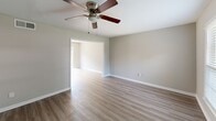 This two-story, 2-bedroom, 2-bathroom home in Forest Park, GA offers a practical and well-appointed layout across two floors. The main level features a welcoming living room with durable hardwood-style laminate flooring and a ceiling fan, which opens into an adjacent space for seamless flow. The kitchen is outfitted with white shaker cabinetry, light marble-look countertops, a subway tile backsplash, stainless steel appliances including a refrigerator and dishwasher, and a stainless steel sink beneath a window that brings in natural light. A carpeted staircase with a white banister leads to the upper level. Both bedrooms are carpeted and feature neutral wall tones, windows with blinds offering outdoor views, and ample closet space — the primary bedroom includes a double bifold closet. The bathrooms are clean and functional, with one featuring a marble-look vanity countertop and mirror, and the other offering a tub/shower combo with a window for ventilation. Throughout the home, neutral gray-beige tones, white trim, and consistent finishes create a cohesive and move-in ready atmosphere.