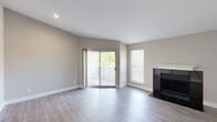 Located at 4000-4040 Presidential Blvd in Philadelphia, PA, this three-bedroom, two-bathroom residence offers a well-designed single-floor layout with a thoughtful blend of modern finishes and functional living spaces. The open living room is a standout, featuring light gray hardwood-style flooring, a striking black-tiled fireplace with a classic white mantel, and sliding glass doors that open to a private outdoor deck with views of surrounding greenery, filling the room with natural light. A dedicated window further brightens the space. The kitchen is designed for efficiency and style, outfitted with two-tone cabinetry — white upper cabinets paired with warm wood lower cabinets — white quartz countertops, a blue tile backsplash, stainless steel appliances including a refrigerator, dishwasher, range, and microwave, plus a convenient breakfast bar. A louvered utility closet is accessible nearby. The three bedrooms feature plush carpeting and neutral walls, with the primary bedroom offering access to a walk-in closet. The bathrooms are finished with large-format tile flooring, wood-toned vanities, white quartz countertops, and clean white surrounds. The entrance foyer connects all areas seamlessly, completing this cohesive and move-in-ready home.