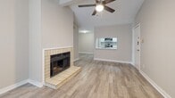 Located at 15215 Blue Ash Dr in Houston, TX, this single-story home offers a well-designed layout with a consistent, modern aesthetic throughout. The living room serves as the heart of the home, showcasing vaulted ceilings accented by exposed beams, a ceiling fan with light kit, and a classic tile-surround fireplace with a raised hearth that adds warmth and character. Wood-look plank flooring flows seamlessly across the main living areas, providing a clean and cohesive look. A pass-through window connects the living space to the kitchen, maintaining an open and airy feel. The galley-style kitchen is efficiently designed, featuring white cabinetry with modern hardware, light quartz-style countertops, a stainless steel sink, and a full suite of stainless steel appliances including a range, microwave, dishwasher, and refrigerator. The bedrooms are generously proportioned, each equipped with a ceiling fan and natural light from windows with blinds. Neutral toned walls throughout the home create a bright, versatile backdrop ready for personalization. A connecting hallway provides clear circulation between the living areas and private rooms. Overall, the home presents a clean, move-in ready environment with practical updates and a comfortable, understated style.