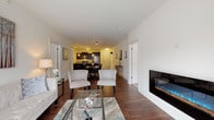 This single-floor residence on Lannon Drive in Muskego, Wisconsin, offers a thoughtfully designed open-concept layout that seamlessly connects the main living areas. Rich, dark hardwood flooring flows throughout the living, dining, and kitchen spaces, lending a warm and cohesive aesthetic.

The living room is anchored by a sleek, wall-mounted electric fireplace and opens directly to the dining area, which comfortably accommodates a large table suited for gatherings. Natural light enters through a sliding glass door at the far end, brightening the entire common area.

The kitchen is a functional and stylish centerpiece, featuring dark espresso cabinetry, granite countertops with a waterfall-edge island, stainless steel appliances, and pendant lighting overhead. Ample counter space makes this kitchen as practical as it is attractive.

The bedroom is a quiet retreat with plush carpeting and a generously sized walk-in closet outfitted with wire shelving on multiple walls, offering extensive storage. The bathroom is finished with granite countertops, light cabinetry, a framed mirror, and a glass-enclosed walk-in shower with tile surround and luxury vinyl plank flooring, creating a clean, spa-like atmosphere.