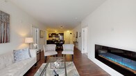 This single-floor residence on Lannon Drive in Muskego, Wisconsin, offers a thoughtfully designed open-concept layout that seamlessly connects the main living areas. Rich, dark hardwood flooring flows throughout the living, dining, and kitchen spaces, lending a warm and cohesive aesthetic.

The living room is anchored by a sleek, wall-mounted electric fireplace and opens directly to the dining area, which comfortably accommodates a large table suited for gatherings. Natural light enters through a sliding glass door at the far end, brightening the entire common area.

The kitchen is a functional and stylish centerpiece, featuring dark espresso cabinetry, granite countertops with a waterfall-edge island, stainless steel appliances, and pendant lighting overhead. Ample counter space makes this kitchen as practical as it is attractive.

The bedroom is a quiet retreat with plush carpeting and a generously sized walk-in closet outfitted with wire shelving on multiple walls, offering extensive storage. The bathroom is finished with granite countertops, light cabinetry, a framed mirror, and a glass-enclosed walk-in shower with tile surround and luxury vinyl plank flooring, creating a clean, spa-like atmosphere.
