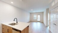 Located at 7325 Quivira Rd in Shawnee, Kansas, this 1-bedroom, 1-bathroom residence offers a thoughtfully designed single-floor layout with modern finishes throughout. The open-concept kitchen and living area serves as the heart of the home, featuring two-tone cabinetry with warm wood lower cabinets and crisp white upper cabinets, a quartz countertop peninsula with an undermount sink and matte black faucet, subway tile backsplash, and stainless steel appliances including a refrigerator, range, microwave, and dishwasher. Light wood-tone flooring extends throughout the main living areas, enhancing the bright and clean aesthetic. The living area benefits from a sliding glass door and adjacent window that invite natural light and provide access to an outdoor balcony with exterior views. The entrance area is welcoming and open, with a window that adds additional daylight. The bedroom is a comfortable retreat finished with plush carpet, a ceiling fan, a large window overlooking the surrounding community, and a closet. The full bathroom is cleanly appointed with a tub-shower combination featuring tile surround, a wood-toned vanity with quartz countertop, and consistent light flooring. Recessed lighting throughout completes the contemporary feel of this well-appointed residence.