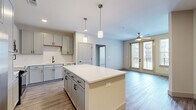 Located at 257 Indian Lake Blvd in Hendersonville, Tennessee, this 2-bedroom, 2-bathroom residence offers a thoughtfully designed single-floor layout with contemporary finishes throughout. The open-concept kitchen and living area serves as the heart of the home, anchored by a large center island with a crisp white countertop and pendant lighting above. The kitchen is equipped with stainless steel appliances, gray shaker-style cabinetry, a subway tile backsplash, and a undermount sink with a matte black faucet. Light wood-look flooring extends through the main living areas, complementing the neutral color palette. The living room features a ceiling fan and glass French doors that open to a private balcony, allowing abundant natural light to fill the space. The primary bedroom is generously sized with plush carpeting, a ceiling fan, and direct access to both a full en-suite bathroom and a spacious walk-in closet with dual wire shelving. The en-suite bathroom features a glass-enclosed walk-in shower, white countertops, and matching gray cabinetry with black hardware. The second bedroom is well-proportioned with carpeting, a ceiling fan, and a bright window. A hallway and two closets provide additional storage throughout the residence.