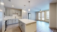 Located at 257 Indian Lake Blvd in Hendersonville, Tennessee, this 2-bedroom, 2-bathroom residence offers a thoughtfully designed single-floor layout with contemporary finishes throughout. The open-concept kitchen and living area serves as the heart of the home, anchored by a large center island with a crisp white countertop and pendant lighting above. The kitchen is equipped with stainless steel appliances, gray shaker-style cabinetry, a subway tile backsplash, and a undermount sink with a matte black faucet. Light wood-look flooring extends through the main living areas, complementing the neutral color palette. The living room features a ceiling fan and glass French doors that open to a private balcony, allowing abundant natural light to fill the space. The primary bedroom is generously sized with plush carpeting, a ceiling fan, and direct access to both a full en-suite bathroom and a spacious walk-in closet with dual wire shelving. The en-suite bathroom features a glass-enclosed walk-in shower, white countertops, and matching gray cabinetry with black hardware. The second bedroom is well-proportioned with carpeting, a ceiling fan, and a bright window. A hallway and two closets provide additional storage throughout the residence.