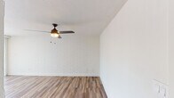 Located at 3130 N 7th Ave in Phoenix, AZ, this single-floor unit offers a practical and well-appointed layout with a clean, updated aesthetic throughout. The main living area is defined by painted white brick walls that add texture and character, complemented by warm wood-look flooring that runs throughout the space. A ceiling fan with a built-in light fixture provides both air circulation and ambient lighting, making the room comfortable year-round in the Arizona climate. Large sliding glass doors allow an abundance of natural light to fill the space while providing direct access to an outdoor area with views of mature landscaping, including palm trees. The kitchen is efficiently designed and features gray shaker-style cabinetry, white subway tile backsplash, a stainless steel refrigerator, electric range, over-the-range microwave, and a single-basin sink — offering a cohesive, modern look. A dedicated closet with a rod and shelf provides convenient storage, while an adjacent hallway leads to the bathroom, which is finished with matching flooring. The textured ceiling, neutral color palette, and consistent use of wood-look flooring throughout create a unified and low-maintenance living environment well-suited to the Phoenix lifestyle.