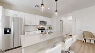 Located at 7850 S Central Ave in Phoenix, AZ, this well-appointed two-story home offers 2 bedrooms and 4 bathrooms across two thoughtfully designed floors. The main level sets an inviting tone with an open-concept kitchen and living area finished in a crisp, contemporary palette. The kitchen is a standout feature, boasting white shaker cabinetry, stainless steel appliances, a large quartz waterfall island with bar seating, and stylish pendant lighting overhead — all complemented by light hardwood flooring. A convenient half bath is also located on the main level, alongside an attached two-car garage with an automatic opener. Upstairs, the layout expands with two bedrooms, additional bathrooms, and a hallway connecting the spaces. The generously sized primary bedroom features plush carpeting, ceiling fan, multiple windows for natural light, and direct access to an outdoor area. Its en-suite bathroom includes a tub-shower combo, white vanity cabinetry, and access to a walk-in closet with built-in shelving and a charming round porthole window. The second bedroom is equally comfortable, with light flooring and ample natural light. Throughout, the home maintains a clean, modern aesthetic with neutral tones, light wood floors, and bright, airy interiors.