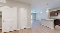 This well-appointed one-bedroom, one-bathroom residence in Kyle, TX offers a thoughtfully designed single-floor layout that maximizes comfort and functionality. Light wood-style flooring flows throughout the main living areas, creating a warm and cohesive aesthetic. The open-concept kitchen and living area form the heart of the home, where a well-equipped kitchen impresses with rich, dark espresso cabinetry, granite-style countertops, a central island with pendant lighting above, and a full suite of black appliances including a refrigerator, range, microwave, and dishwasher. Recessed lighting adds a polished finish overhead. The living room is bright and airy, featuring a ceiling fan and a glass door that opens to a private balcony, allowing natural light to pour in. The spacious bedroom comfortably accommodates a full furniture arrangement, includes a ceiling fan, a window with outdoor views, and is conveniently connected to the full bathroom. The bathroom features large-format tile flooring, a dark wood vanity with ample storage, and clean, neutral finishes throughout. Neutral wall tones and white trim unify the space, lending a clean and modern feel suitable for a variety of interior styles.