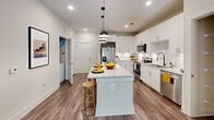 Located at 4521 Landmark Dr in Raleigh, NC, this thoughtfully designed single-floor residence offers a clean, contemporary aesthetic throughout. The heart of the home is a stunning open-concept kitchen outfitted with crisp white shaker cabinetry extending to the ceiling, gleaming granite countertops, a large central island with seating, and a full suite of stainless steel appliances including a French door refrigerator, electric range, built-in microwave, and dishwasher. Stylish pendant lighting and recessed fixtures illuminate the space, while wood-look flooring adds warmth and continuity. The bedroom is a serene retreat, featuring soft neutral tones, a ceiling fan, and large windows that invite natural light and offer leafy outdoor views. Direct access to an en-suite bathroom enhances privacy and convenience. The bathroom is well-appointed with granite-topped white vanity cabinetry, a soaking tub with tiled surround, wood-look flooring, and a generously sized walk-in closet with built-in shelving and organizational systems. Throughout the residence, the design strikes a balance between modern finishes and comfortable livability, creating an inviting and functional home in the heart of Raleigh.