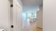 Located at 212 Durham Ave in Metuchen, NJ, this well-appointed 2-bedroom, 2-bathroom residence offers a thoughtfully designed single-floor layout with generous living space. Light wood flooring runs throughout, creating a warm and cohesive aesthetic across every room.

The open-concept kitchen and living area serves as the heart of the home. The kitchen is outfitted with stainless steel appliances — including a French door refrigerator, microwave, and range — complemented by white upper cabinetry, gray lower cabinetry, and a large central island with a white quartz countertop and pendant lighting above. The living area features access to a private balcony through a glass-paneled door, bringing in natural light and outdoor views.

The primary bedroom is a comfortable retreat with multiple windows fitted with white blinds, a ceiling fan with light fixture, and direct access to a walk-in closet featuring wire shelving on multiple walls. The second bedroom also benefits from abundant natural light and its own closet with wire rack storage.

Both bathrooms are finished with light wood-style flooring, white quartz vanity countertops, and matte black fixtures. One bathroom features a soaking tub with tiled surround, while the other includes a glass-enclosed walk-in shower with white subway tile.