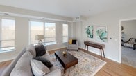This thoughtfully designed single-floor residence offers a seamless blend of modern finishes and comfortable living. The open-concept layout connects the living, dining, and kitchen areas, all anchored by warm hardwood-style flooring that flows throughout the main spaces. Large windows invite an abundance of natural light, creating a bright and welcoming ambiance across the living and dining areas.

The kitchen is a standout feature, boasting rich dark granite countertops, crisp white cabinetry, a subway tile backsplash, and a full suite of stainless steel appliances including a gas range, built-in microwave, and a French door refrigerator. A generously sized island with seating provides both additional prep space and a casual dining option.

The bedroom is a tranquil retreat, finished with plush carpeting and featuring direct access to a spacious walk-in closet. Windows with roller shades allow for adjustable natural light throughout the day. Two well-appointed bathrooms continue the home's refined aesthetic, each featuring granite-topped vanities, hardwood-style flooring, and tub-shower combinations with brushed nickel fixtures.

A cozy secondary sitting area rounds out the space, offering a quiet nook ideal for relaxation or reading, complete with carpeted flooring and an exterior-facing window.