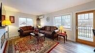 Located in Waite Park, Minnesota, this single-floor, one-bedroom, one-bathroom space offers a thoughtfully designed layout that maximizes comfort and functionality. The open-concept kitchen and living area serves as the heart of the home, featuring crisp white cabinetry, granite-style countertops, stainless steel appliances, and a central island that doubles as a casual dining space. Light wood-tone flooring runs throughout, lending warmth and continuity to the entire unit.

The main living room is generously sized and bathed in natural light from multiple large windows. A standout stone-surround electric fireplace anchors the room, providing both a visual focal point and a cozy ambiance. A secondary living area offers additional flexible space, also featuring a wall-mounted mini-split unit for personalized climate control.

The bedroom is a comfortable retreat, complete with a window for natural light, a wall-mounted mini-split system, and ample space for furnishings. The bathroom is tastefully finished with a white vanity, an arched mirror, modern black fixtures, soft sage-green walls, and a tub-shower combination — all accented by light hardwood-style flooring. Every room reflects a clean, modern aesthetic with warm, welcoming touches throughout.