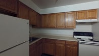 Located at 835 Blooming Grove Tpke in New Windsor, New York, this single-floor unit offers a practical and straightforward layout designed for comfortable everyday living. The kitchen is a standout functional space, featuring an abundance of warm oak cabinetry that spans both upper and lower sections, providing generous storage throughout. The L-shaped counter configuration maximizes workspace efficiency, with light-toned laminate countertops offering a clean and neutral surface. Essential appliances are included, among them a full-size refrigerator and an electric range, making the kitchen move-in ready. The under-cabinet space is well-utilized, and the layout allows for ease of movement during meal preparation. The neutral wall tones throughout contribute to a clean, understated aesthetic that allows for personalization. The single-floor design ensures convenient accessibility, with no stairs to navigate between living areas. Overall, the space presents a no-frills, utilitarian character well-suited to those seeking a straightforward and functional home base in the New Windsor area of New York's Hudson Valley region.