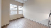 Located at 2111 S Wabash Ave in Chicago's vibrant South Loop neighborhood, this single-floor unit offers a clean, modern aesthetic with a well-considered layout. The kitchen is a standout feature, outfitted with a full suite of stainless steel appliances including a full-size refrigerator, over-the-range microwave, cooktop, and dishwasher. Sleek white cabinetry extends from counter height to the elevated ceiling, maximizing storage while maintaining a minimalist, contemporary look. Light-toned hardwood flooring runs throughout the unit, lending warmth and continuity to the space. The bedroom is a bright and open room, benefiting from a pair of windows that draw in natural light and offer views of the surrounding brick streetscape. The bathroom is efficiently designed, featuring a modern vessel-style sink, a mirrored medicine cabinet with vanity lighting, chrome fixtures, and a full tub-shower combination. Exposed ductwork in the kitchen area adds an industrial design element that complements the building's urban character. The overall ambiance is clean, contemporary, and functional, making it well-suited for city living in one of Chicago's most accessible and dynamic neighborhoods.