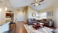 This single-story, 3-bedroom, 2-bathroom home offers a thoughtfully designed layout that maximizes comfort and functionality. The living room serves as the heart of the home, featuring soaring vaulted ceilings with a ceiling fan, crown molding, rich hardwood flooring, and a bright window that invites natural light. The open-concept kitchen and living area flow seamlessly together, anchored by a curved granite-topped island with a built-in sink, warm cherry wood cabinetry, pendant lighting, and direct sightlines into the living space — ideal for both everyday living and entertaining. The primary bedroom is generously sized, featuring hardwood floors, crown molding, and a large window with neighborhood views. Its en-suite bathroom includes a glass-enclosed walk-in shower, and an adjacent walk-in closet outfitted with wire shelving provides ample storage. The additional bedrooms are well-proportioned and bright, each benefiting from multiple windows and neutral tones. A dedicated closet offers extra storage for the household. Throughout, consistent hardwood flooring, crown molding, and a warm neutral color palette create a cohesive and inviting atmosphere across the entire home.