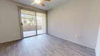 This single-floor, 1-bedroom, 1-bathroom unit offers a thoughtfully designed layout that maximizes both functionality and comfort. The combined kitchen and living area serves as the heart of the home, with light gray wood-style flooring flowing throughout. The kitchen is outfitted with dark cabinetry contrasted by white countertops, a full suite of stainless steel appliances — including a refrigerator, range, and microwave — and a single-basin sink, creating a sleek, modern aesthetic. The living area opens directly onto a private balcony through sliding glass doors dressed with vertical blinds, allowing abundant natural light to fill the space. A ceiling fan overhead adds to the comfort of the room. The bedroom features plush carpeting, a ceiling fan, a window with vertical blinds, and a built-in desk with cabinetry, making it a versatile and practical retreat. The bathroom is clean and straightforward, featuring a tub-shower combo, a dark-cabinet vanity with a white countertop, and wood-style tile flooring. A dedicated in-unit laundry area houses a full-size front-loading washer and dryer with overhead shelving. Additional storage is provided by a separate closet, rounding out this efficiently planned space.