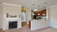 Located at 2620 Rockport Ln in Naperville, Illinois, this single-floor home offers a well-designed layout with warm, neutral tones and comfortable finishes throughout. The open-concept living and kitchen area serves as the heart of the home, where a granite-topped breakfast bar peninsula anchors the space. The kitchen is outfitted with rich cherry-toned cabinetry, stainless steel appliances including a gas range, microwave, and refrigerator, and elegant pendant lighting that adds a polished touch. The adjacent living area features plush carpeting and a classic tile-surround fireplace with a white mantel, creating an inviting atmosphere. Crown molding throughout adds a refined architectural detail. Bedrooms are generously proportioned, carpeted for comfort, and equipped with ceiling fans. Large windows dressed with blinds allow natural light to filter in, offering pleasant outdoor views. The bathroom is finished with granite countertops, rich wood cabinetry, a large framed mirror, and a shower-tub combination, maintaining the consistent quality seen throughout the home. Hardwood flooring accents the kitchen and bathroom areas, complementing the overall warm and welcoming character of this Naperville residence.