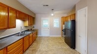Located at 4015 Summer Ave in Memphis, Tennessee, this single-story, 2-bedroom, 1-bathroom home offers a practical and comfortable layout across a compact, efficiently organized floor plan. The kitchen is a functional galley-style space featuring warm honey-toned wood cabinetry, ample upper and lower cabinet storage, a double-basin sink, and tile flooring. A back door and two windows allow natural light to fill the kitchen area. Adjacent to the kitchen, a spacious living and dining area features durable hardwood-style flooring, neutral wall tones, and a window providing views of the outdoors. The two bedrooms are carpeted and finished in warm beige tones, each offering a closet and overhead lighting. The primary bedroom is generously proportioned, while the second bedroom also includes a window for natural light. A connecting hallway links the rooms seamlessly. The shared bathroom is thoughtfully finished with floor-to-ceiling large-format tile surrounding a soaking tub and combination showerhead, complemented by chrome fixtures and a window for ventilation and natural light. Throughout the home, neutral color palettes and clean lines create a simple, welcoming ambiance well-suited for comfortable everyday living.