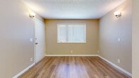 Located at 505 Heather Ln in Newton, Kansas, this single-story unit offers a straightforward, functional layout across several well-defined spaces. The floor plan, visible in the overhead model, reveals a compact yet efficiently organized arrangement that includes a main living area, kitchen, bedroom spaces, a bathroom, and a dedicated laundry room.

The living and entry areas are finished with warm beige walls, clean white trim, and light wood-look flooring that carries consistently throughout the unit. Windows fitted with horizontal blinds allow natural light to filter into these spaces, contributing to a bright and neutral ambiance. Wall-mounted sconce lighting provides additional illumination throughout.

The kitchen features white cabinetry with ample upper and lower storage, a double-basin stainless steel sink, light countertops, and a full-size refrigerator. The flooring continues seamlessly from the main living areas into the kitchen.

The bathroom includes a full-size soaking tub with a white surround, chrome fixtures, and a clean, functional design. A dedicated laundry room provides washer and dryer hookups, a dryer vent, and a window for ventilation. The bedroom areas share the same consistent flooring and neutral wall tones, each with windows providing natural light. Textured ceilings appear throughout the unit.