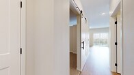 Located at 1130 Hazeltine Boulevard in Chaska, MN, this one-bedroom, one-bathroom residence offers a thoughtfully designed layout that maximizes every square foot. The open-concept living and kitchen area is anchored by light wood-style flooring that flows throughout the main living spaces, creating a bright and cohesive feel. Natural light enters through large windows, enhancing the airy, welcoming ambiance.

The kitchen is a standout feature, equipped with contemporary wood-grain cabinetry in a rich gray-brown tone, stainless steel appliances including a refrigerator, range, over-the-range microwave, and dishwasher, complemented by crisp white quartz countertops and a classic white subway tile backsplash. Recessed lighting adds a polished finishing touch overhead.

A stylish sliding barn door with matte black hardware separates the bedroom from the main living area, adding a modern design element. The carpeted bedroom provides a cozy retreat with ample wall space and direct access to the hallway and closet.

The bathroom features a wood-grain vanity with white countertop, a full soaking tub with shower, and clean white finishes throughout, accented by matte black fixtures and hardware. A dedicated hallway connects all rooms, contributing to an efficient and functional floor plan throughout this well-finished residence.