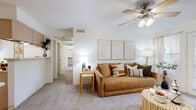 This single-floor residence offers a thoughtfully designed layout that balances comfort and functionality. The living room serves as the heart of the home, featuring plush carpeting, a ceiling fan with light fixture, and a welcoming atmosphere enhanced by natural light from a glass exterior door. The open sightlines connect seamlessly to a hallway leading to the rest of the unit.

The kitchen is efficiently arranged with wood-toned cabinetry, white countertops, a stainless steel refrigerator, an electric range, a built-in dishwasher, and a single-basin sink. Durable wood-look flooring runs throughout, and additional storage is accessible via a nearby closet with built-in shelving.

The primary bedroom is generously sized with soft carpeting, a walk-in closet, and a window that admits natural light. A second bedroom offers versatile space, also carpeted, with a window and wall-mounted shelving. Both rooms maintain a calm, neutral palette.

Two full bathrooms serve the residence, each featuring a tub-shower combination, wood-look flooring, a vanity with storage, and an overhead cabinet. The overall design is clean and consistent, with white walls and warm wood accents tying each room together into a cohesive, livable space.