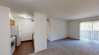 Located at 3004 Ravens Crest Drive in Plainsboro, NJ, this single-floor residence offers a well-organized, functional layout across several thoughtfully designed rooms. The open living area is generously proportioned, featuring wall-to-wall carpeting and a sliding glass door with vertical blinds that invite natural light and provide outdoor access. A half-wall partition separates the living space from the kitchen, creating a semi-open feel while maintaining distinct zones. The kitchen is efficiently designed with warm oak cabinetry, dark granite-style countertops, hardwood-style vinyl flooring, and white appliances including a full-size refrigerator and oven range, along with a sink overlooking the pass-through. The bedrooms are carpeted and bright, each featuring windows with views of surrounding greenery, offering a calm and natural atmosphere. Closet storage is accessible throughout. Two full bathrooms feature clean white tile surrounds with tub-shower combinations and chrome fixtures. A dedicated laundry area with stacked washer and dryer units adds everyday convenience. The overall aesthetic is clean and neutral, with white walls throughout creating a bright, move-in-ready environment well-suited for comfortable everyday living.